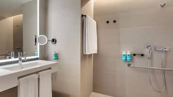 Un baño moderno con lavamanos, espejo, toallero y zona de ducha.