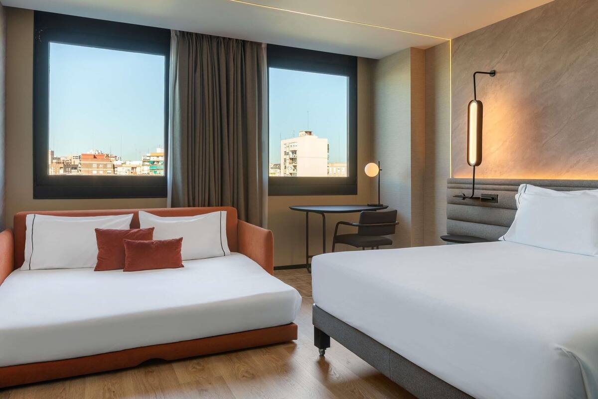 Une chambre d’hôtel avec un lit, un canapé, une petite table et une vue sur la ville.