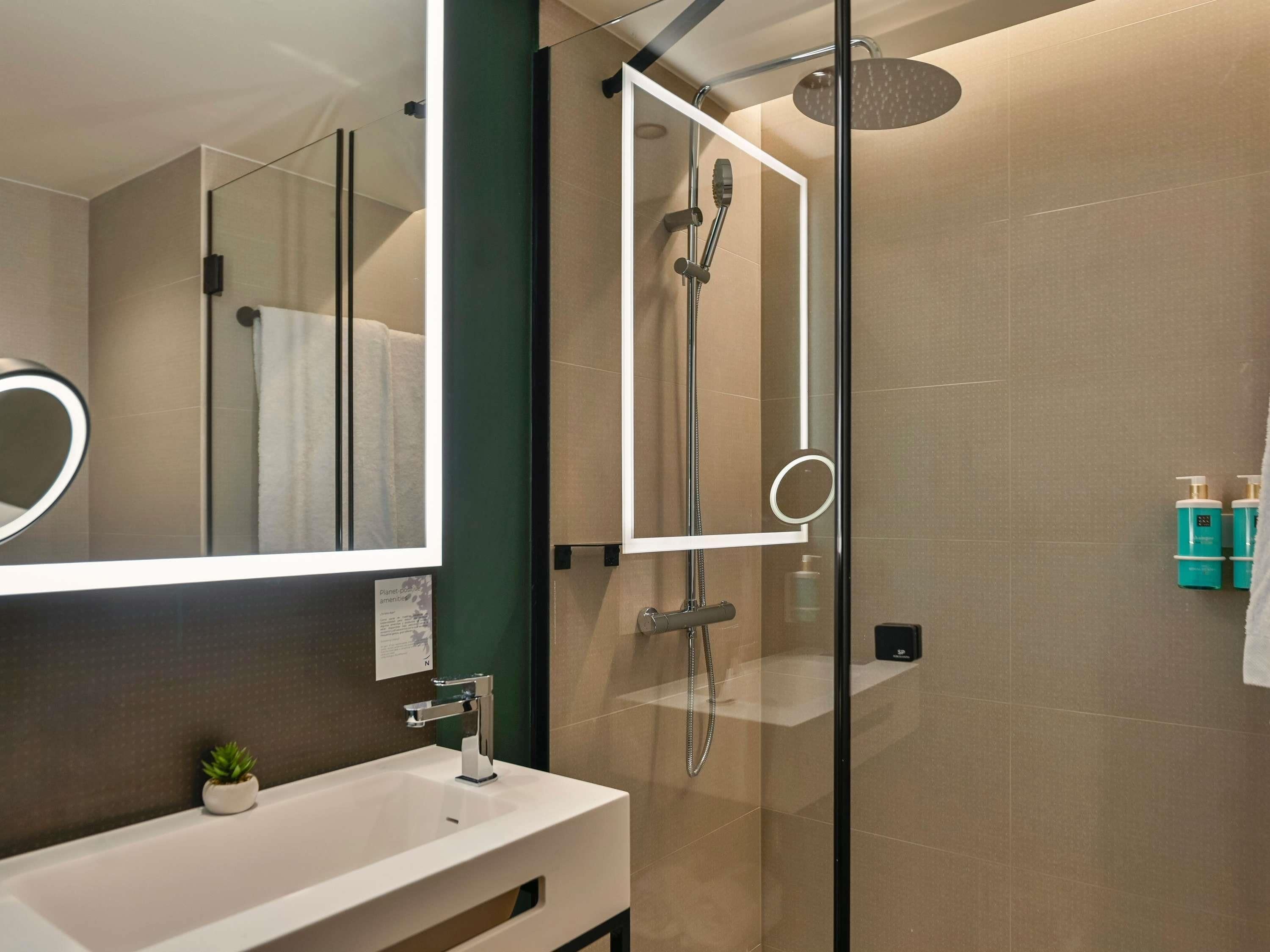 Une salle de bain moderne avec une douche à parois de verre, un lavabo blanc et un miroir.