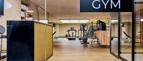 A gym with exercise equipment, a wooden floor, and a sign that reads "GYM".