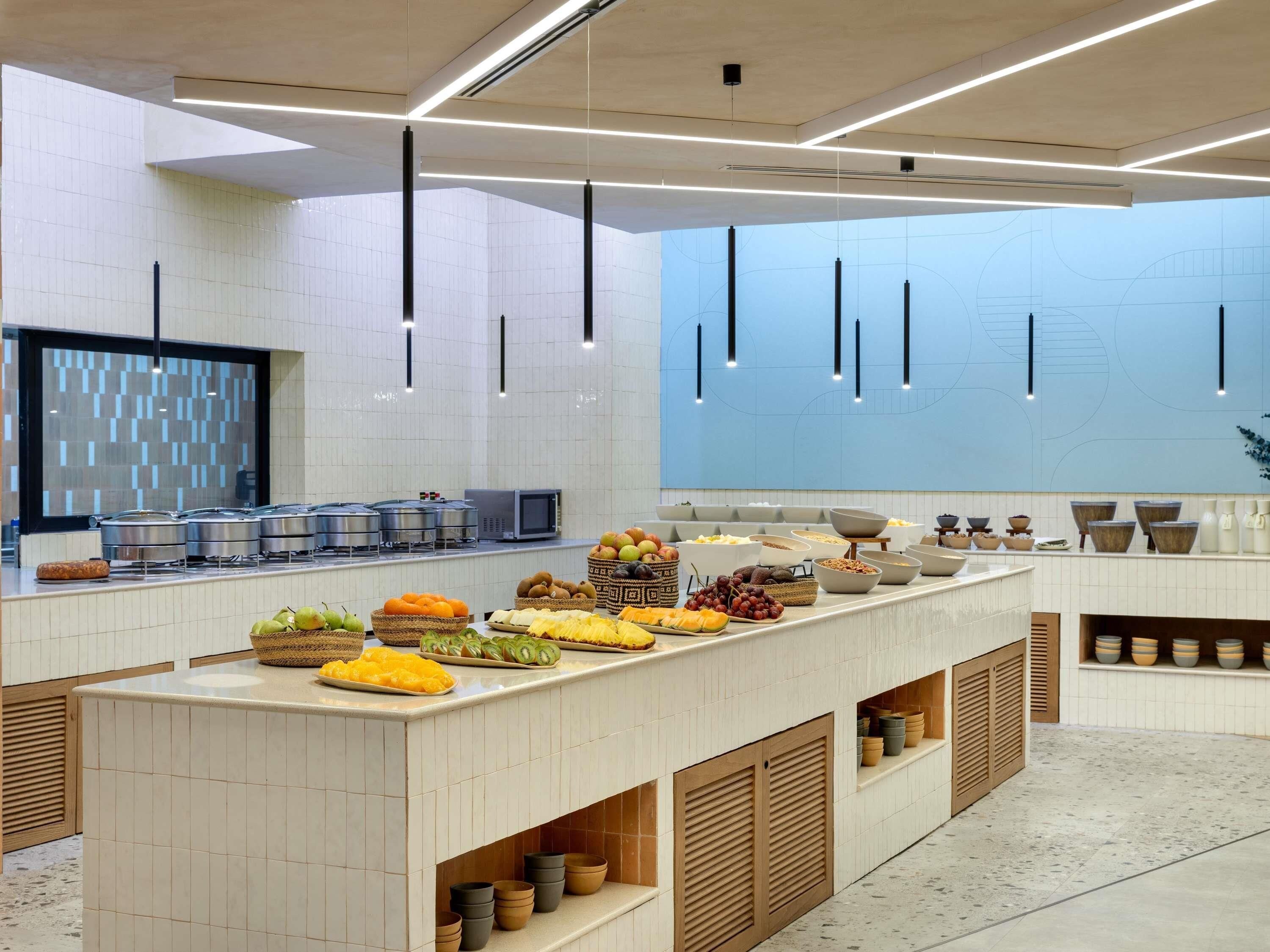 A modern kitchen with a central island, stainless steel appliances, and a variety of food items displayed.