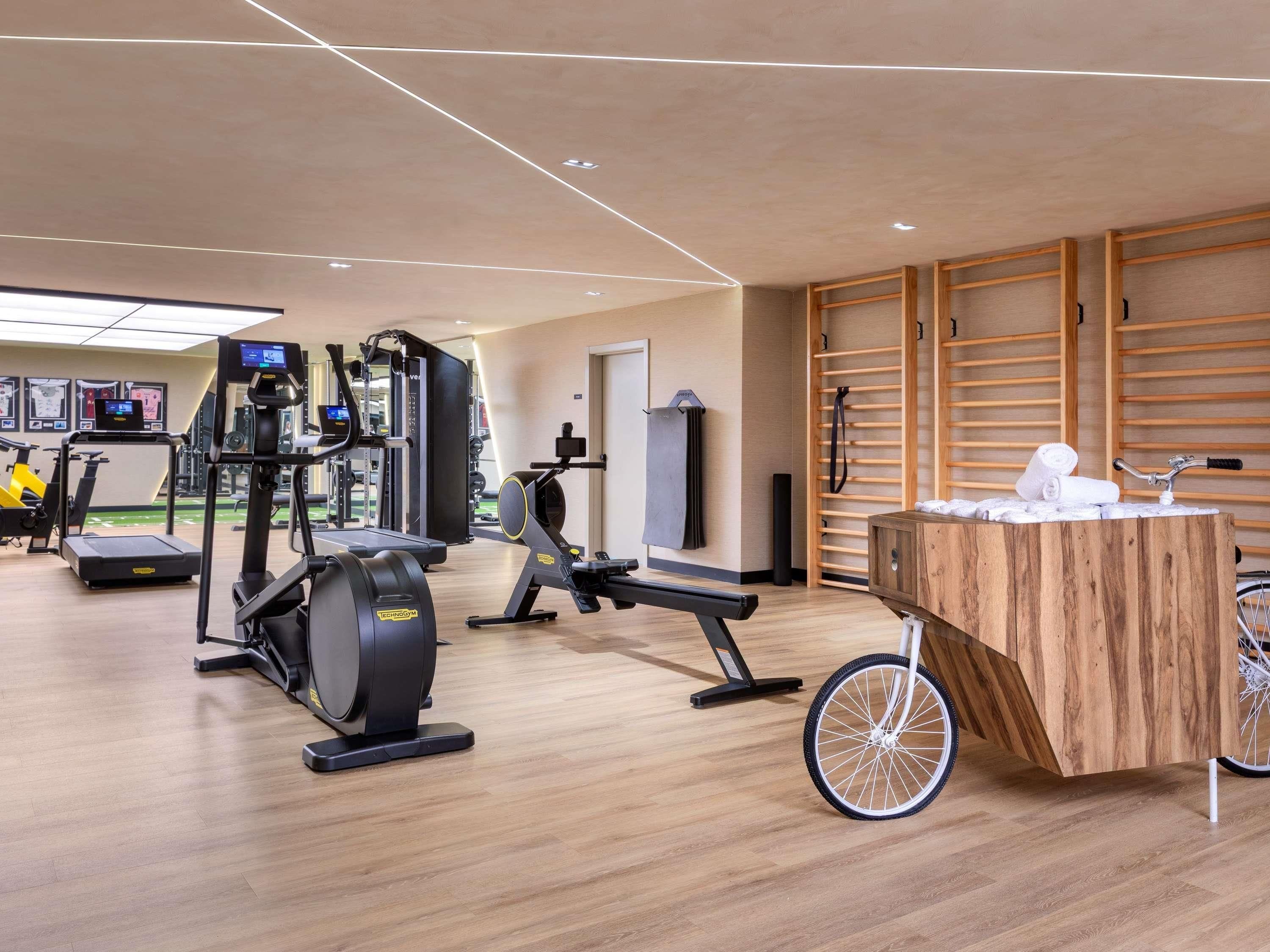Een moderne sportschool met cardiotoestellen, een roeimachine en een houten balie met handdoeken.