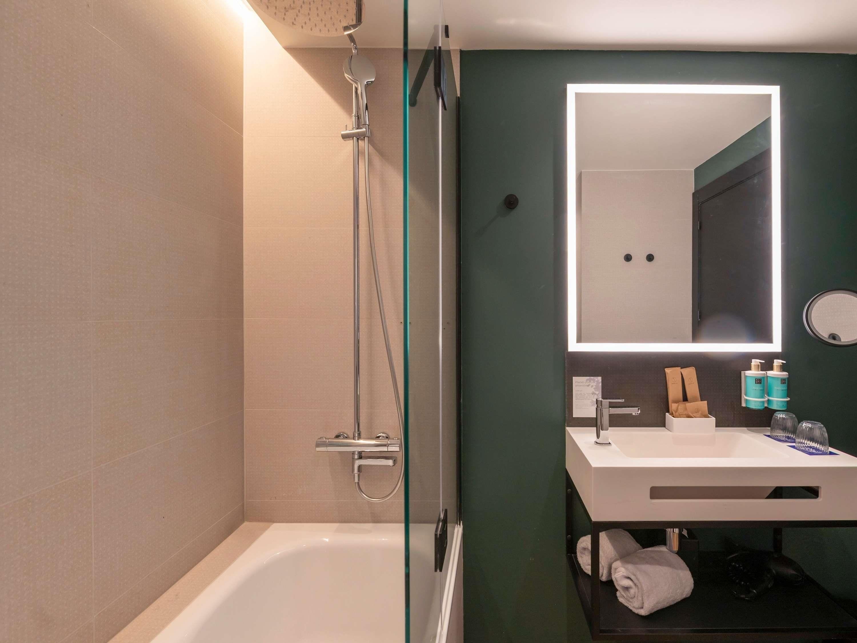 Un bagno con doccia vetrata, una vasca da bagno bianca, un lavabo con specchio e articoli da toilette sul mobile.