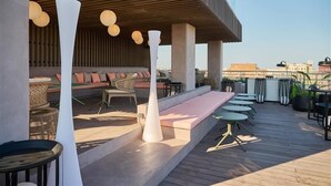 Terraza en la azotea con zonas de estar, mesas y plantas en macetas.