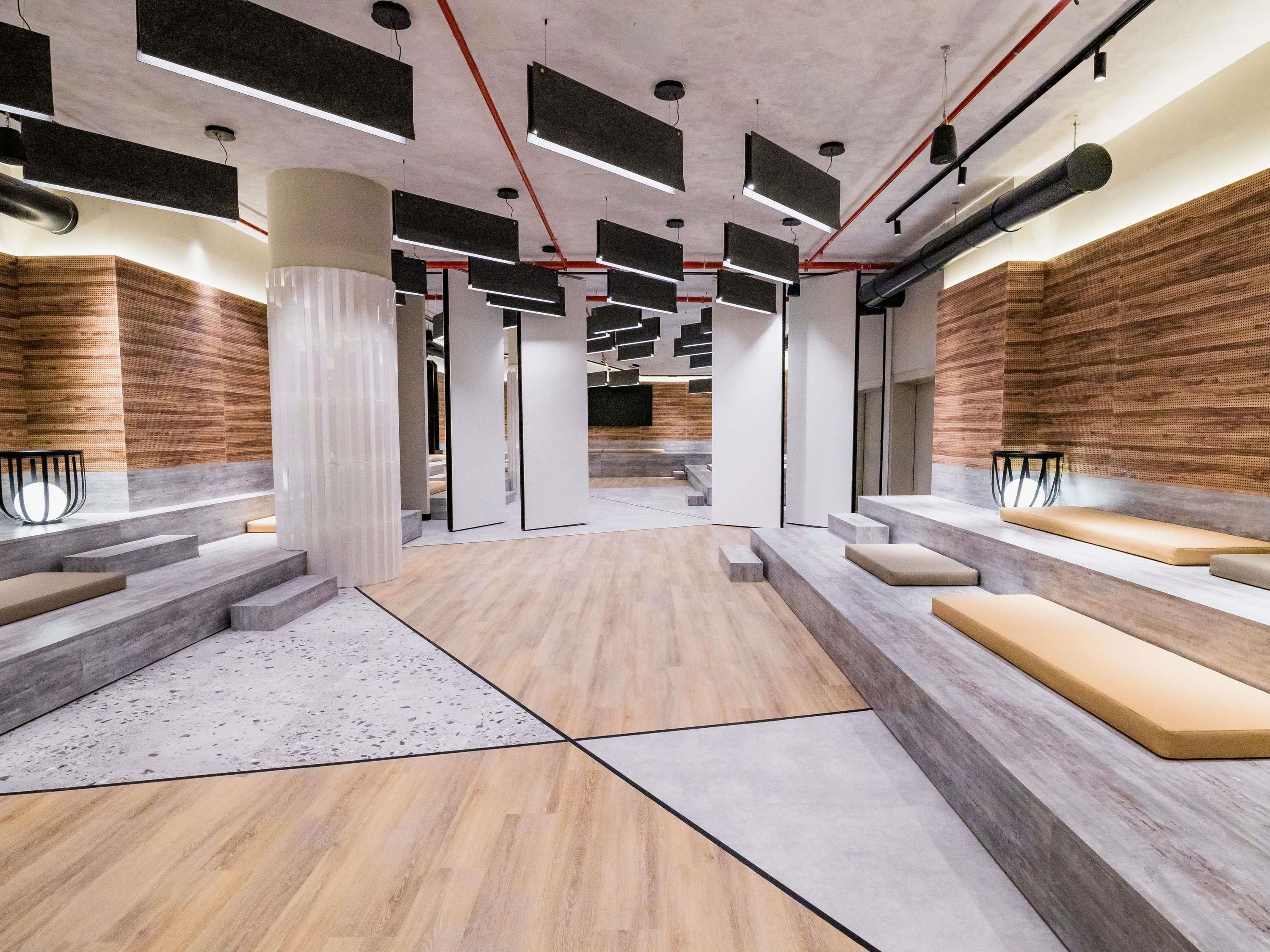 A modern interior with a central staircase, wooden panel walls, and a mix of concrete and wood flooring.