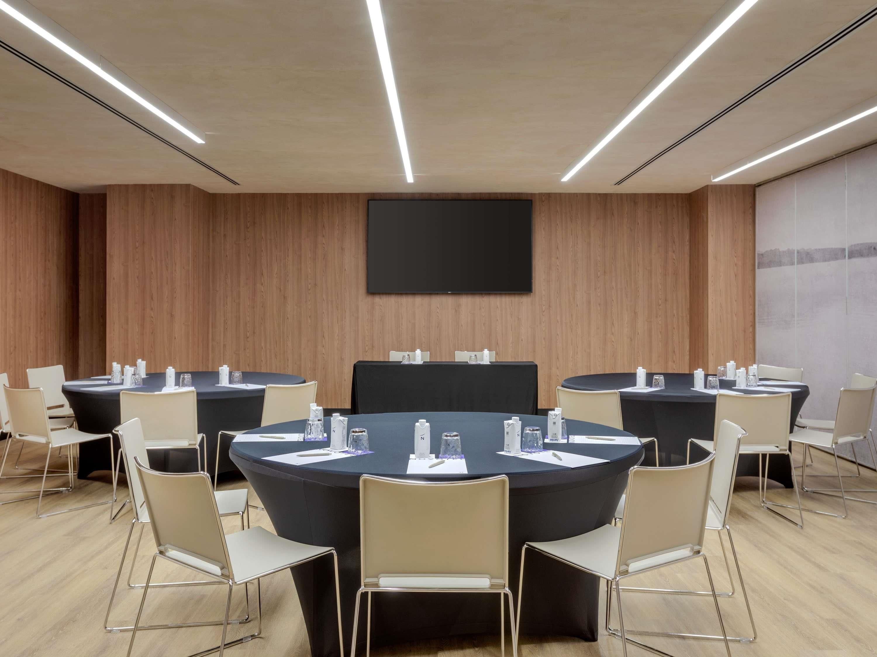A conference room with round tables, chairs, and a large screen on the wall.
