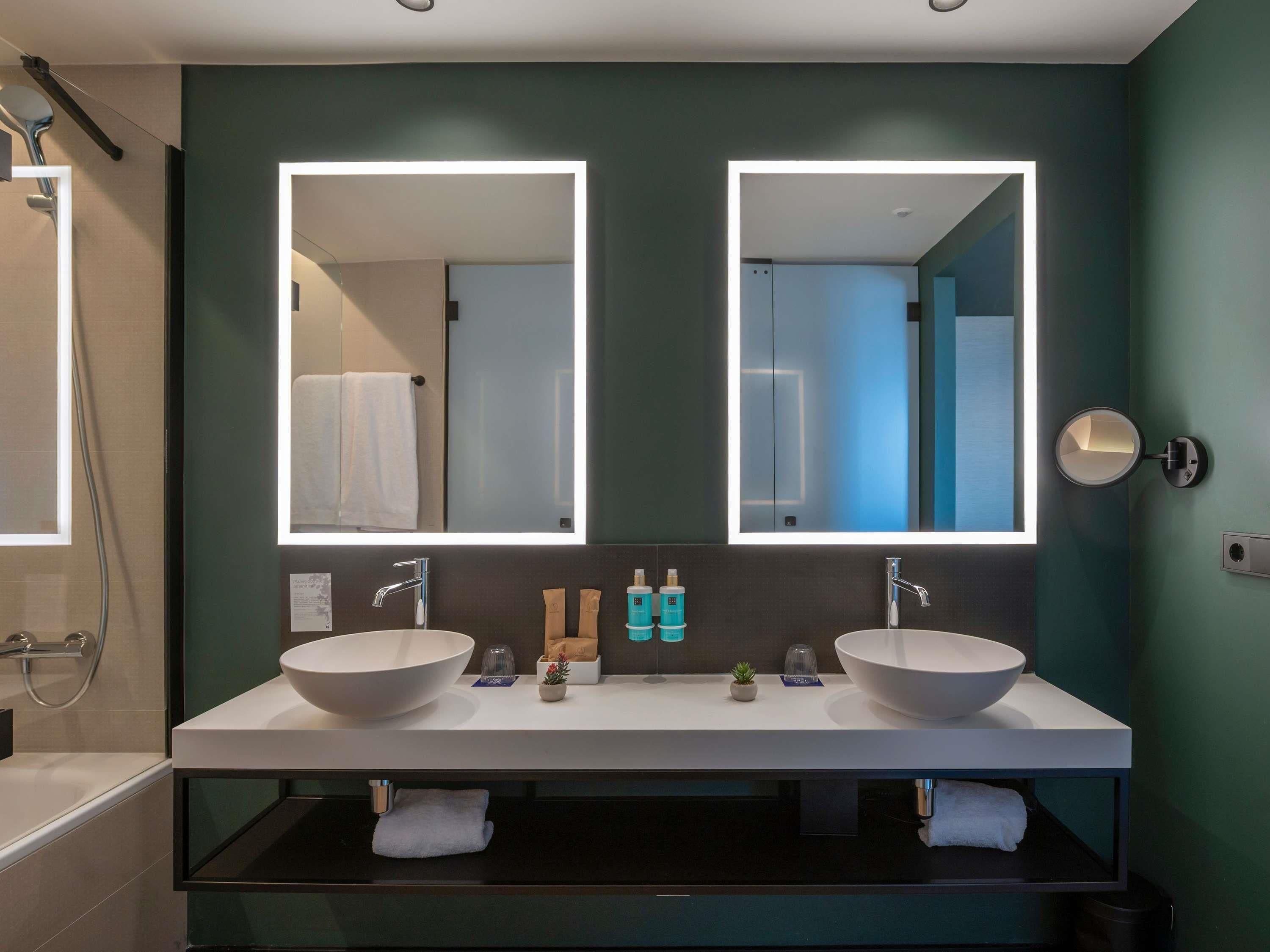 A modern bathroom with two sinks, a large mirror, and a shower.