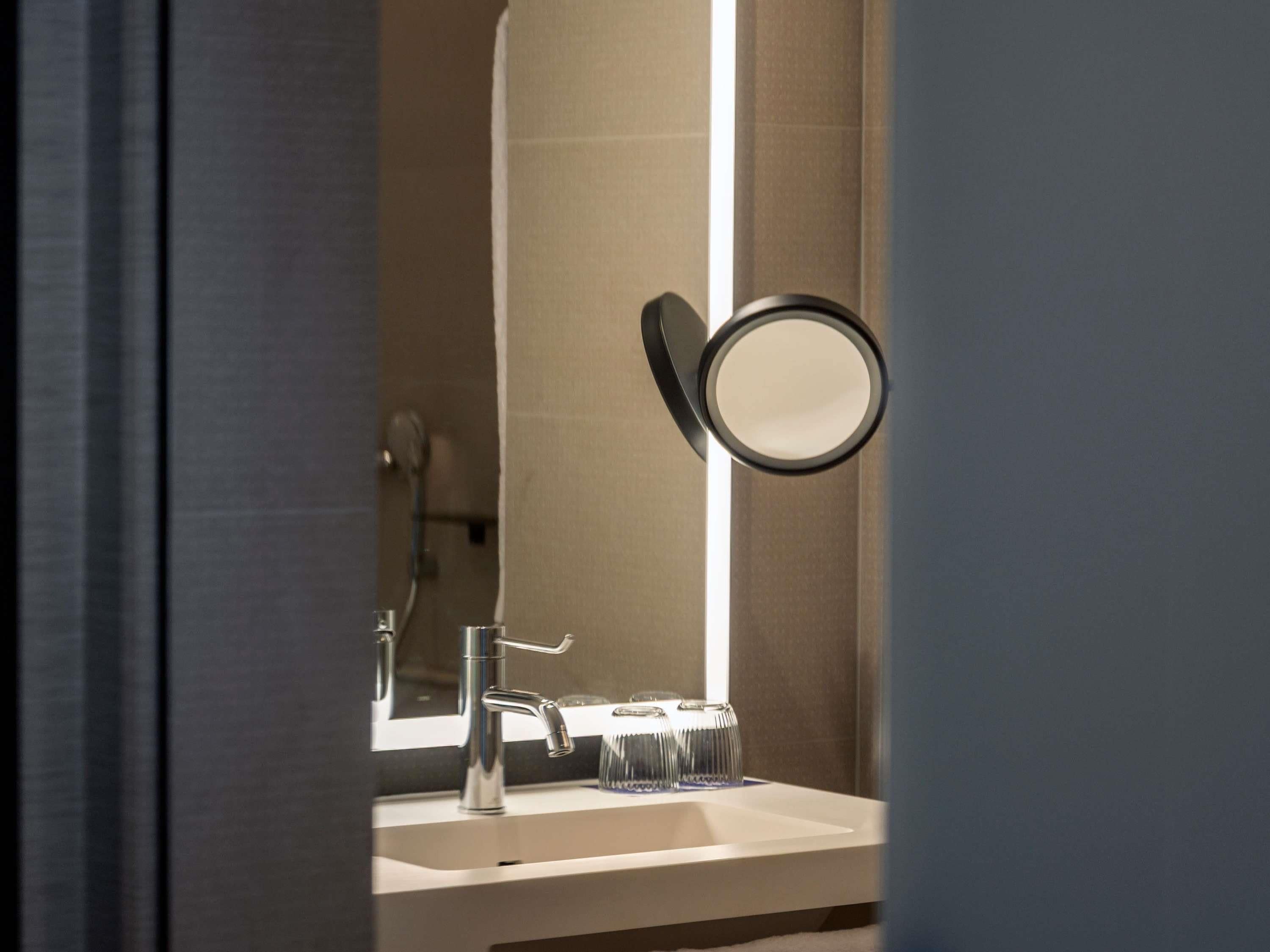 Un bagno con specchio, lavandino e porta asciugamani.