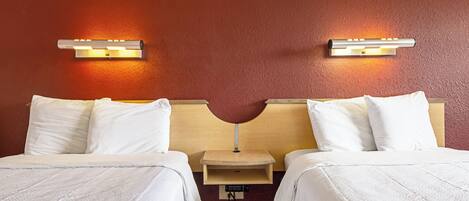A hotel room with two beds, a wooden headboard, a nightstand, and wall-mounted reading lights.