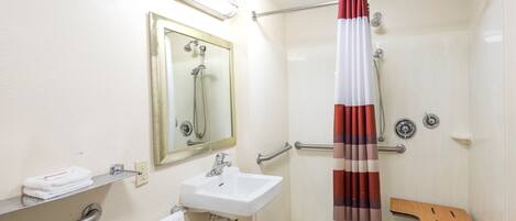 A bathroom with a sink, mirror, shower, and a towel rack.