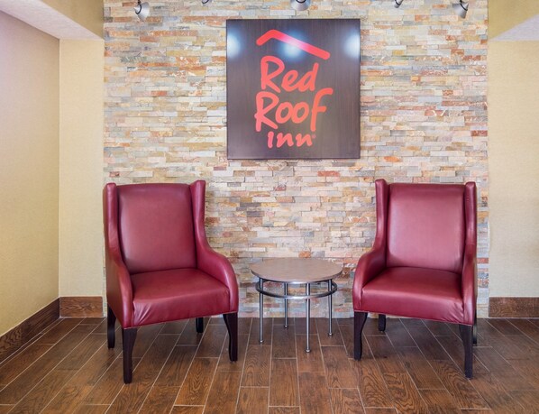 A Red Roof Inn lobby with two leather chairs and a small round table. - Red Roof Inn Jacksonville - Orange Park (Jacksonville)