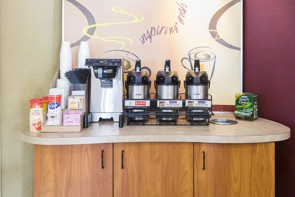 A coffee station with multiple coffee machines, a water dispenser, and various coffee pods. - Red Roof Inn Jacksonville - Orange Park (Jacksonville)