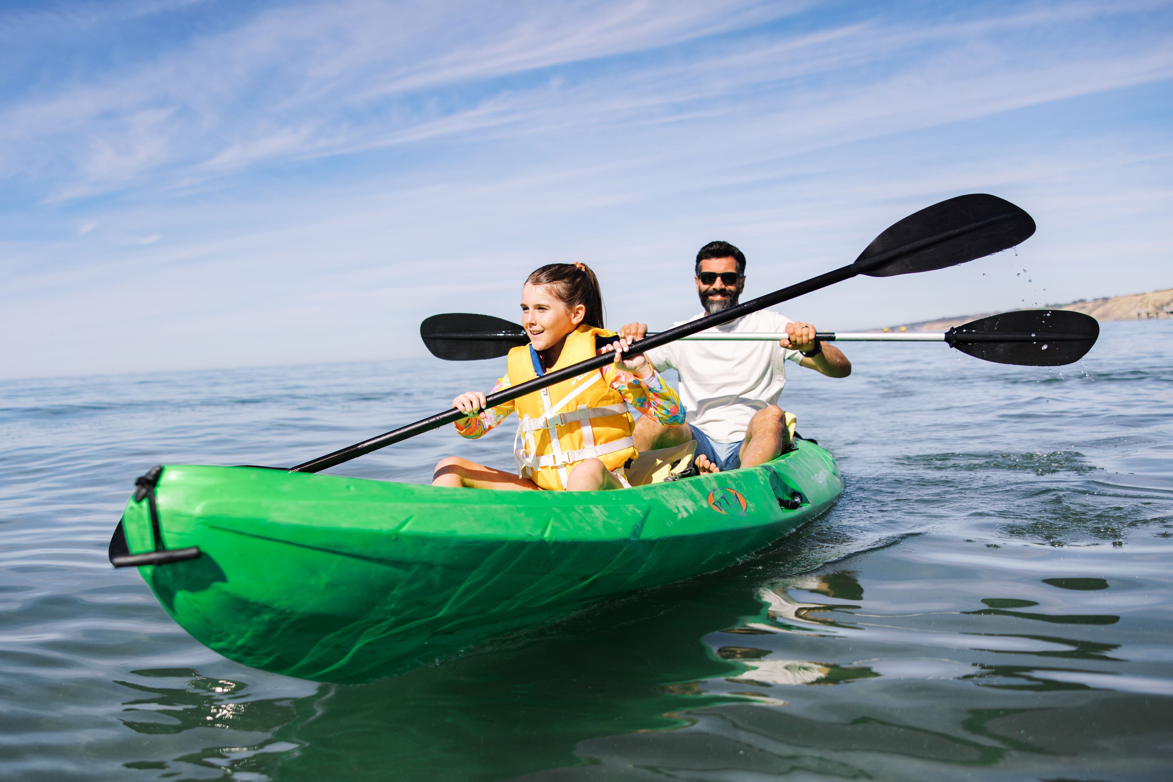 Una pareja en kayak verde sobre aguas tranquilas.