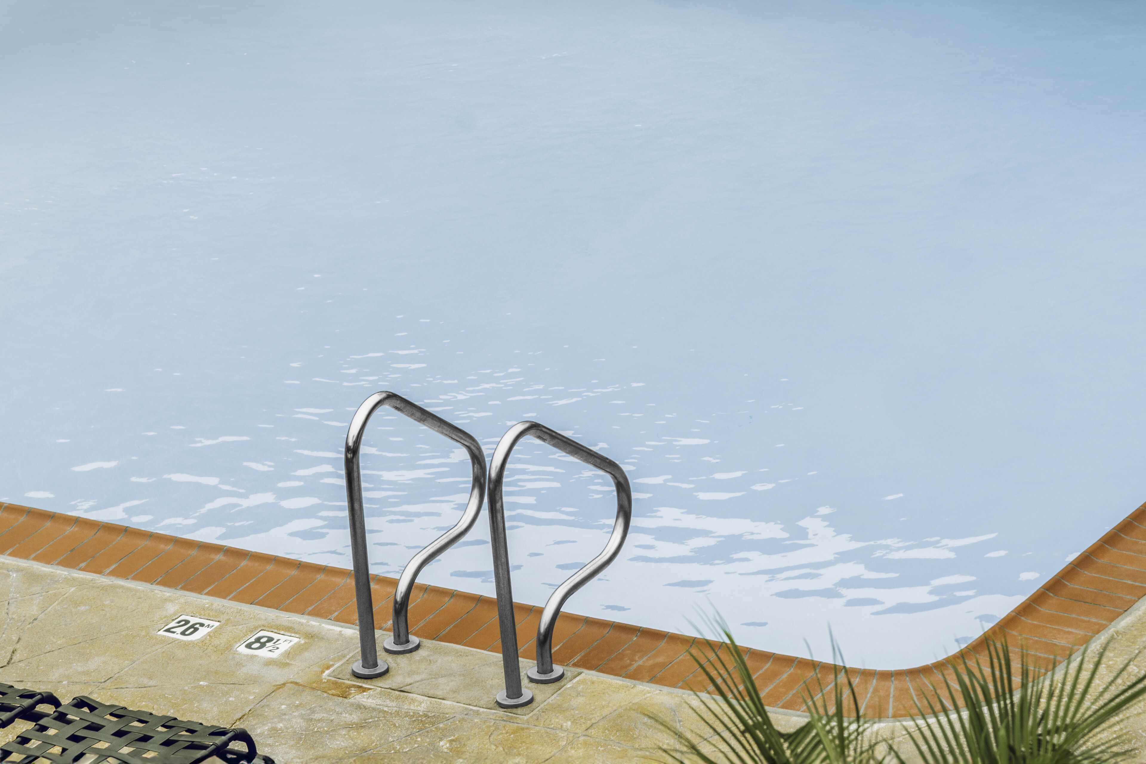 Una piscina con barandales de metal y un borde de azulejos.