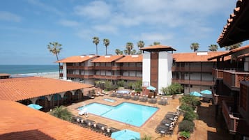 Una piscina al aire libre, sombrillas, sillones reclinables de piscina