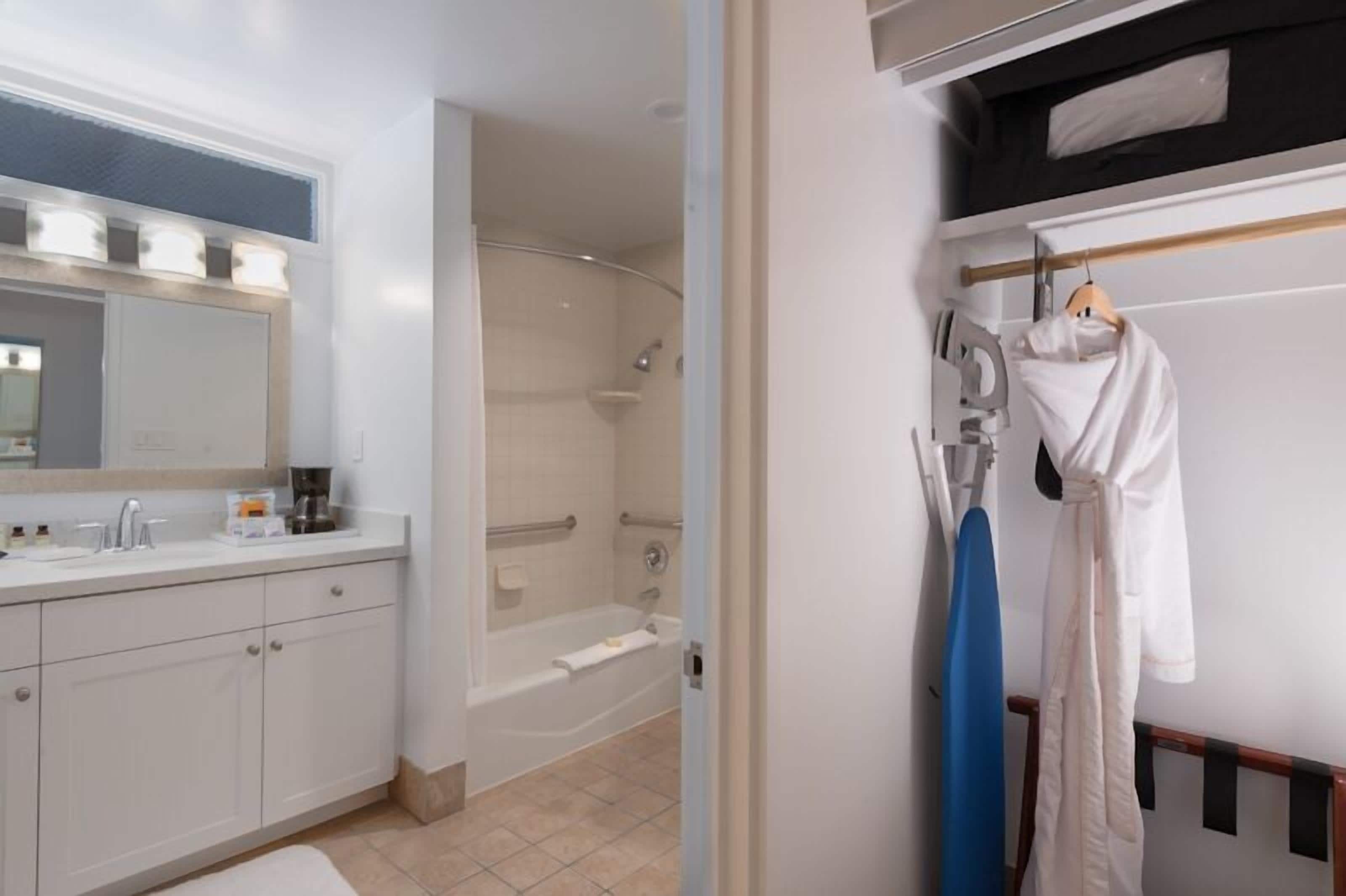 A modern bathroom with a bathtub, a shower, a sink with a mirror, and a towel rack with a robe.
