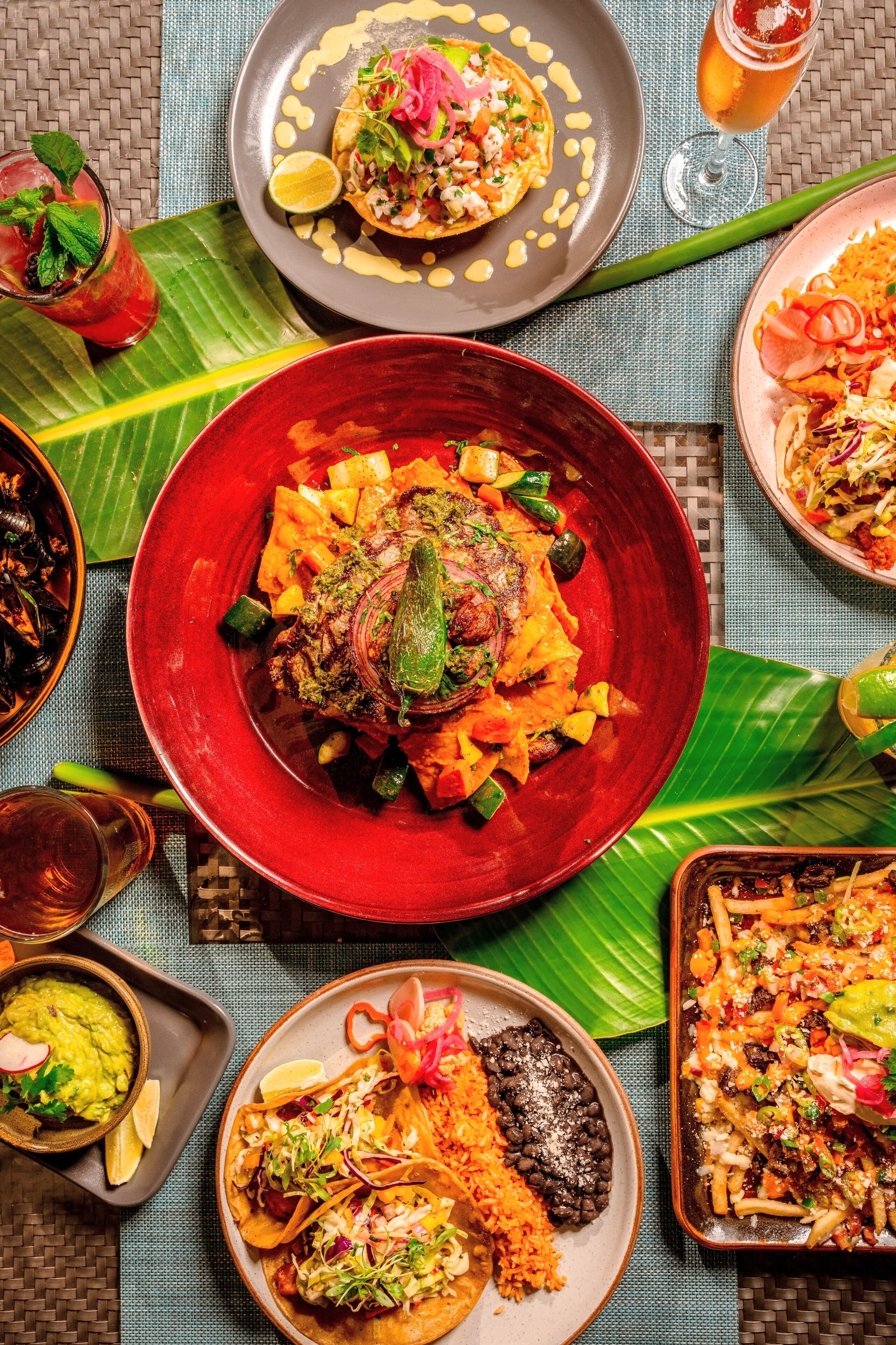 Piatti vari, tra cui tacos, riso e fagioli, serviti su un tavolo con sottopiattino intrecciato.