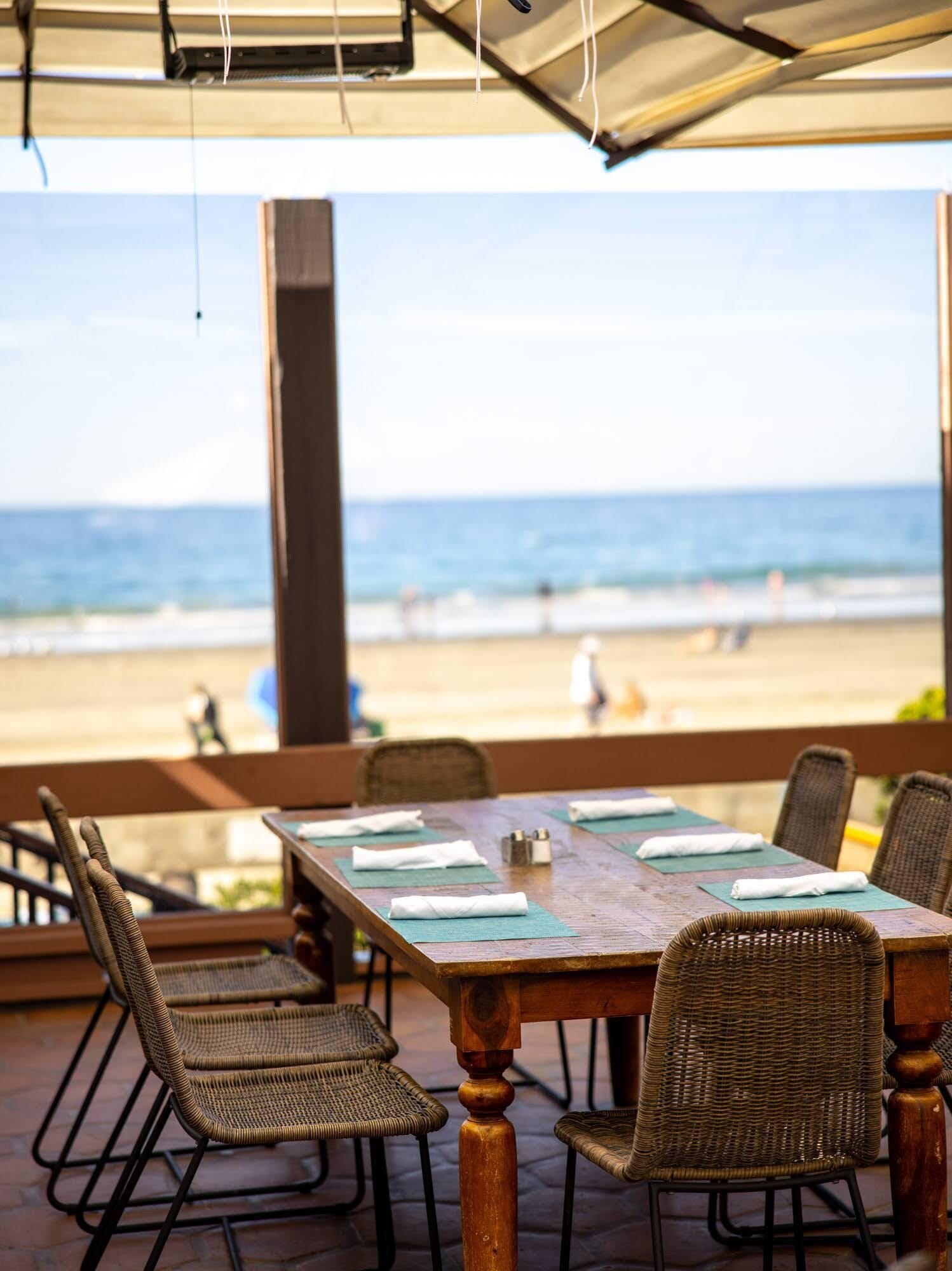 An outdoor dining area with a view of the beach and ocean.