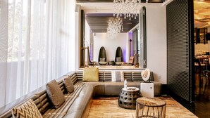 Een moderne woonkamer met een hoekbank, een ronde salontafel en een kroonluchter.