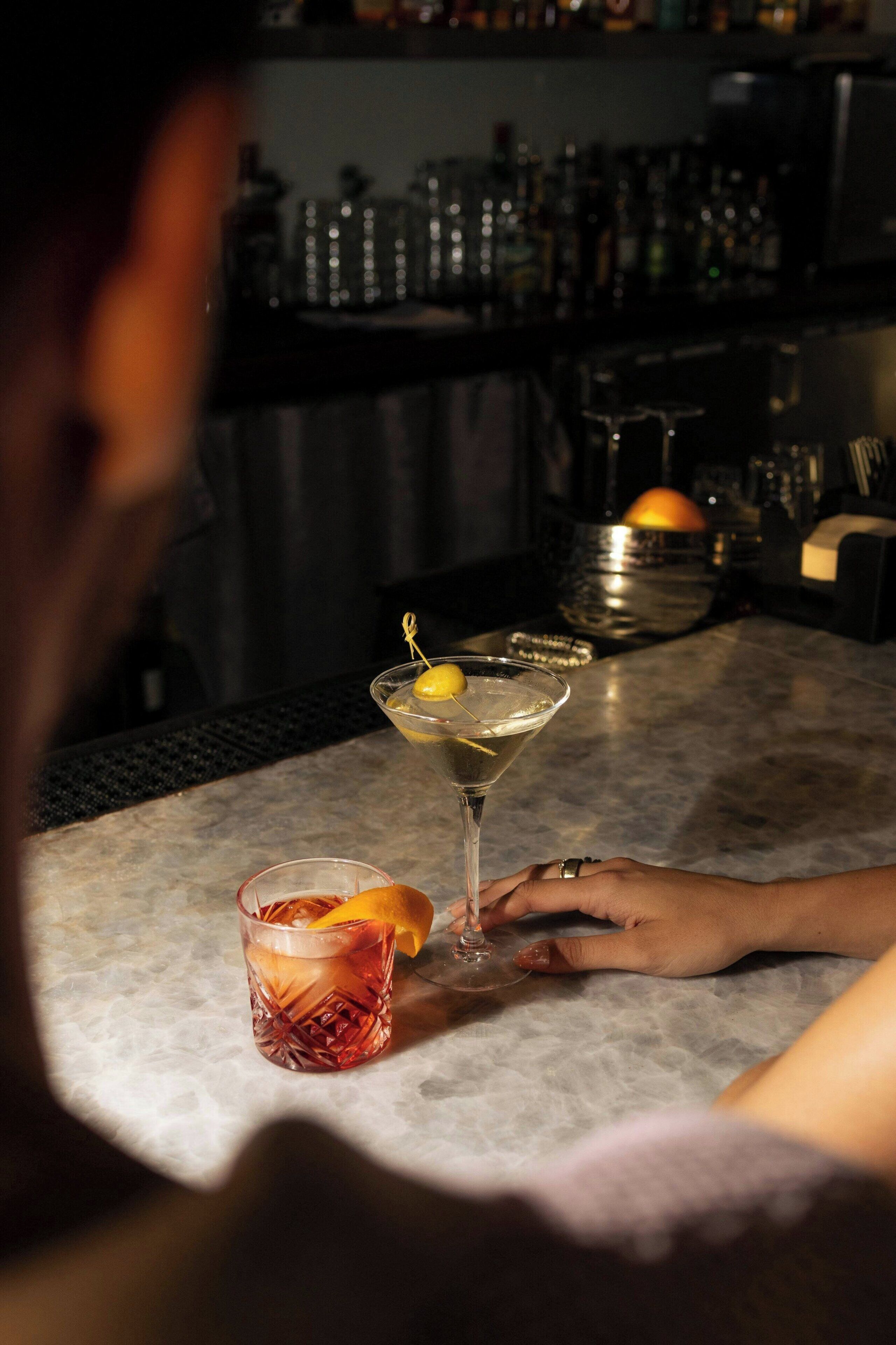 Une scène de bar où une personne tient un verre à cocktail.
