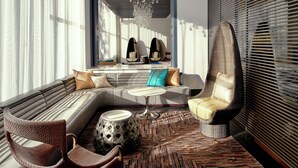 Een moderne woonkamer met een hoekbank, twee fauteuils, een salontafel en een kamerkleed met een patroon.