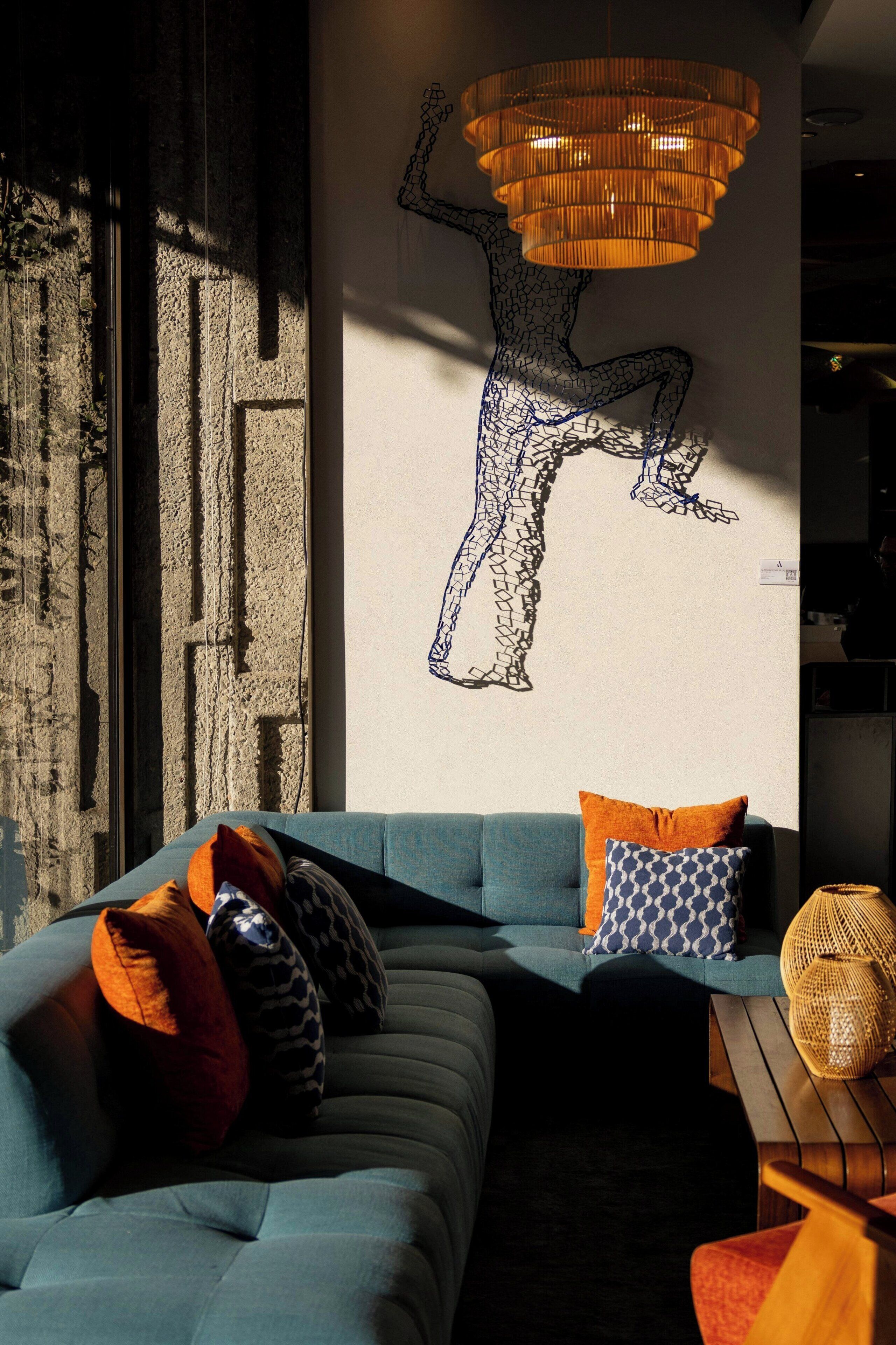 A modern living room with a blue sofa, patterned cushions, a wall art piece, and a textured wall.