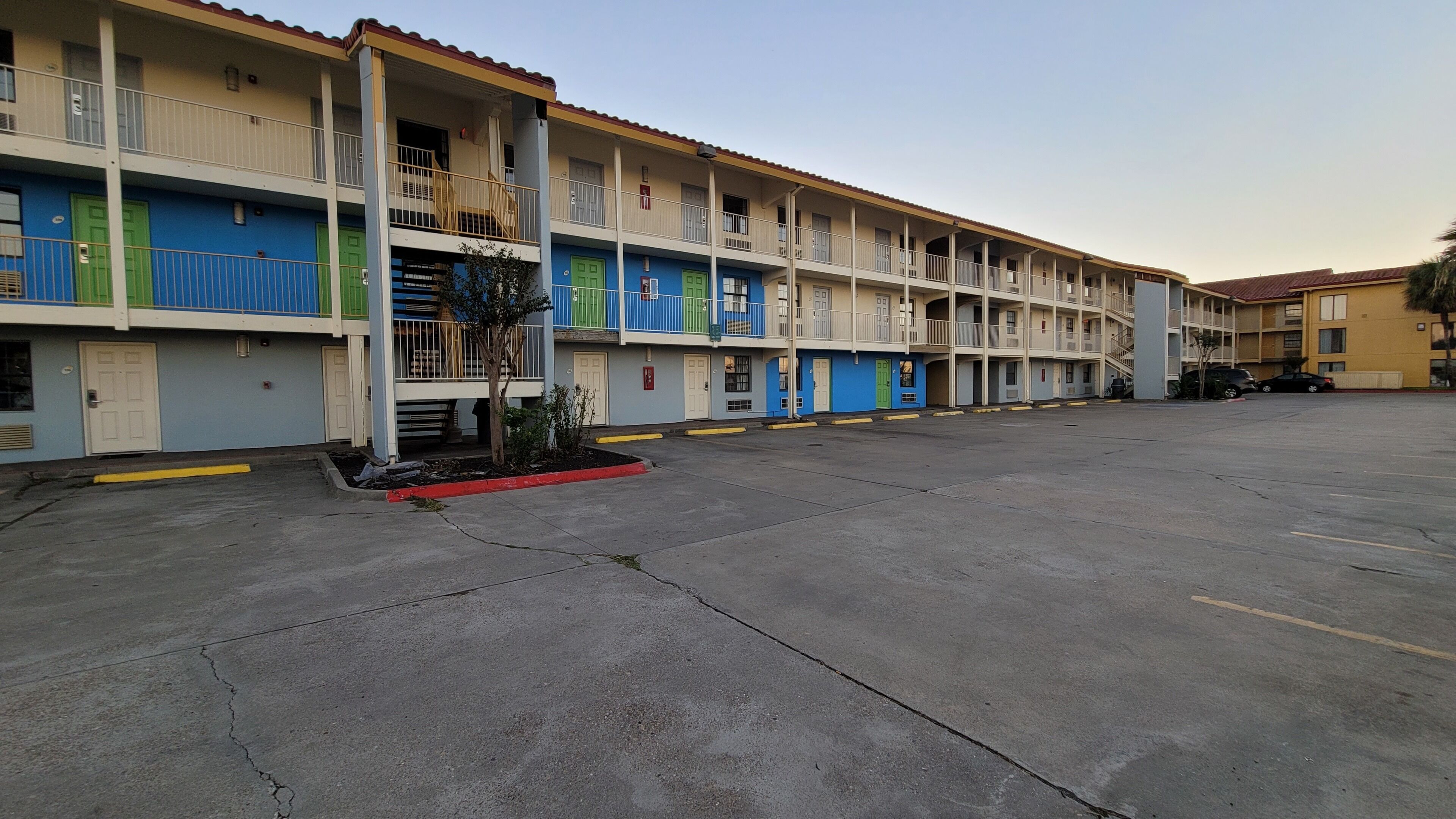 Ein mehrstöckiges Hotel mit Innenhof, Balkonen und Parkplätzen.