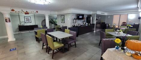 A restaurant with a bar area, multiple tables and chairs, and a tiled floor.