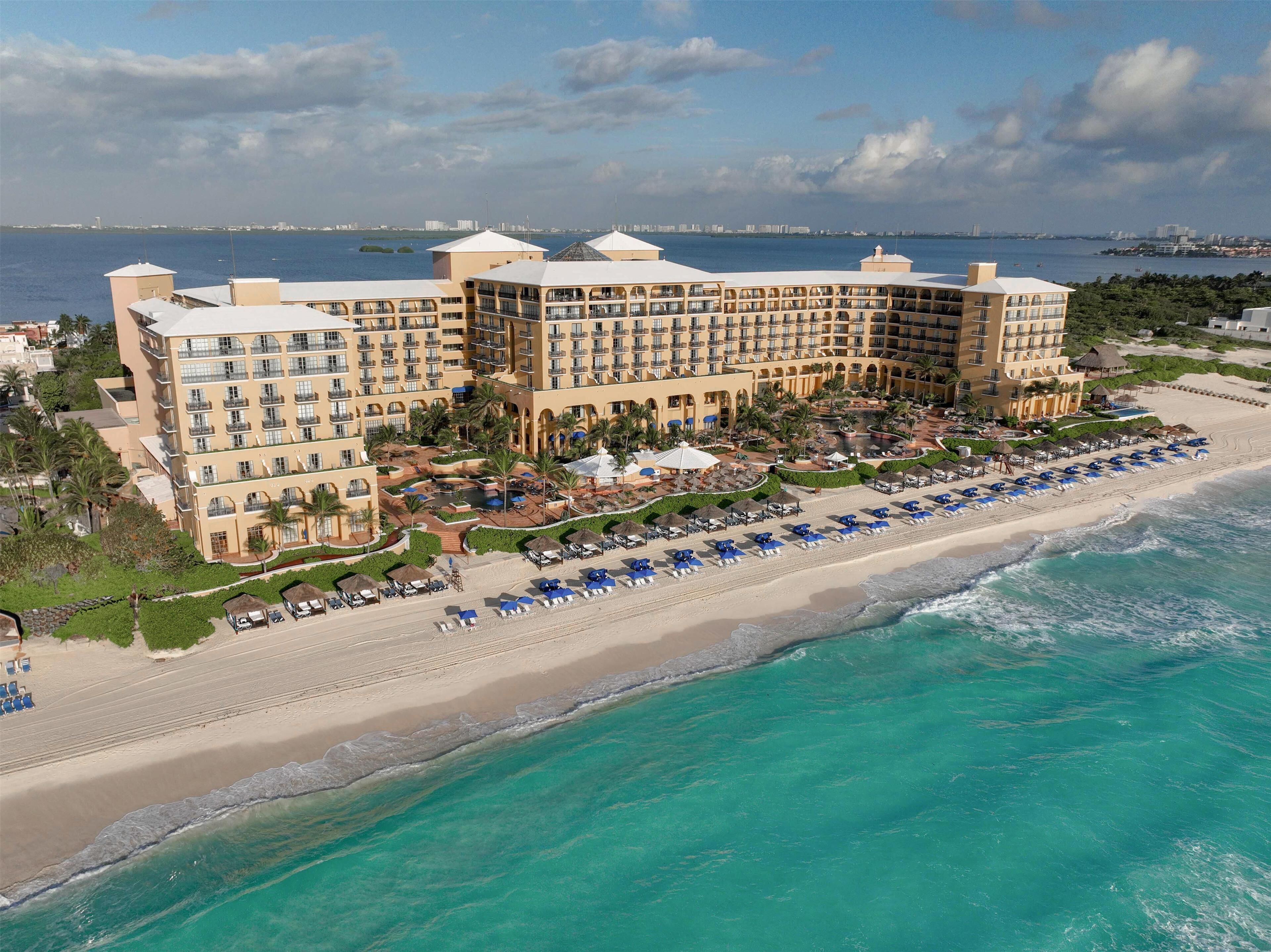 A large hotel with multiple floors, a beachside location, and a pool area.