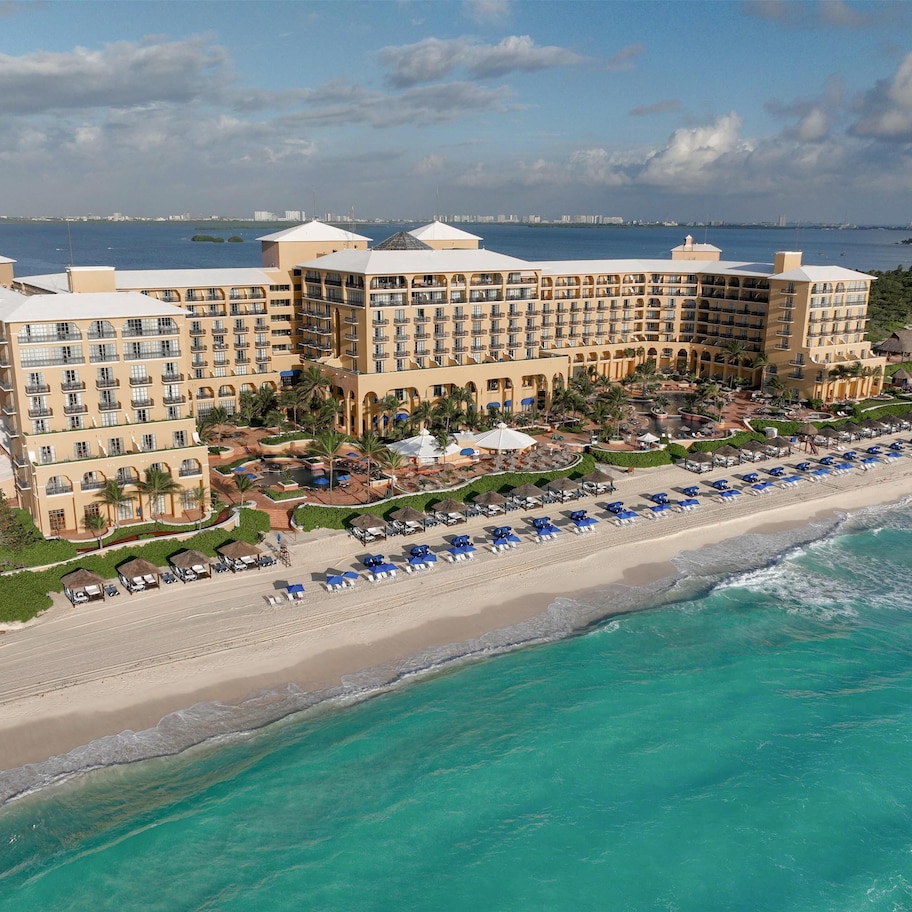 A large hotel with multiple floors, a beachside location, and a pool area.