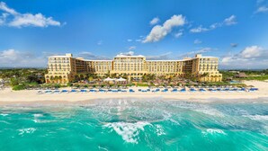 Un gran hotel resort con múltiples balcones, ubicación frente a la playa y vista al océano.