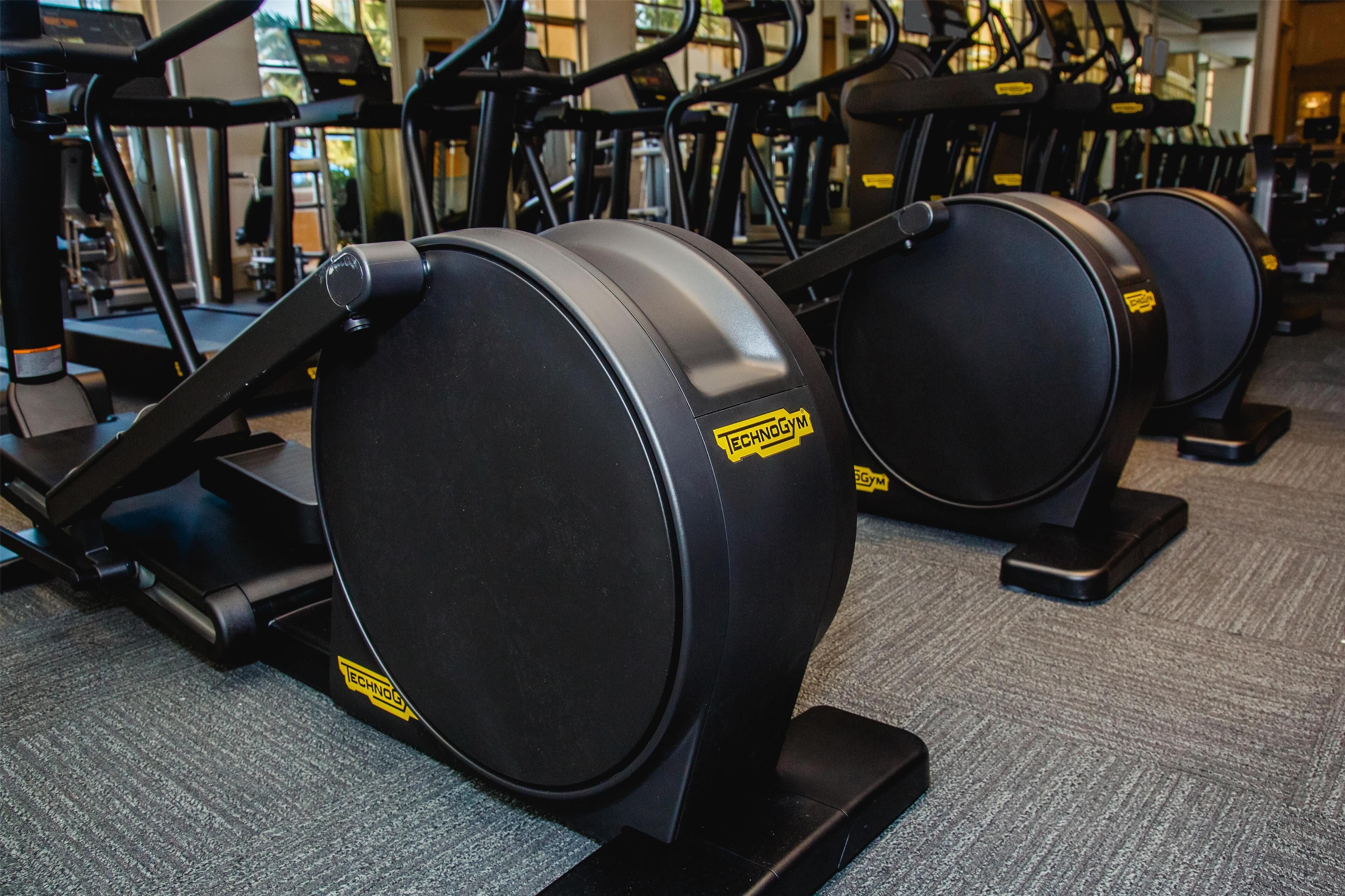 A row of stationary bikes in a gym with a carpeted floor.