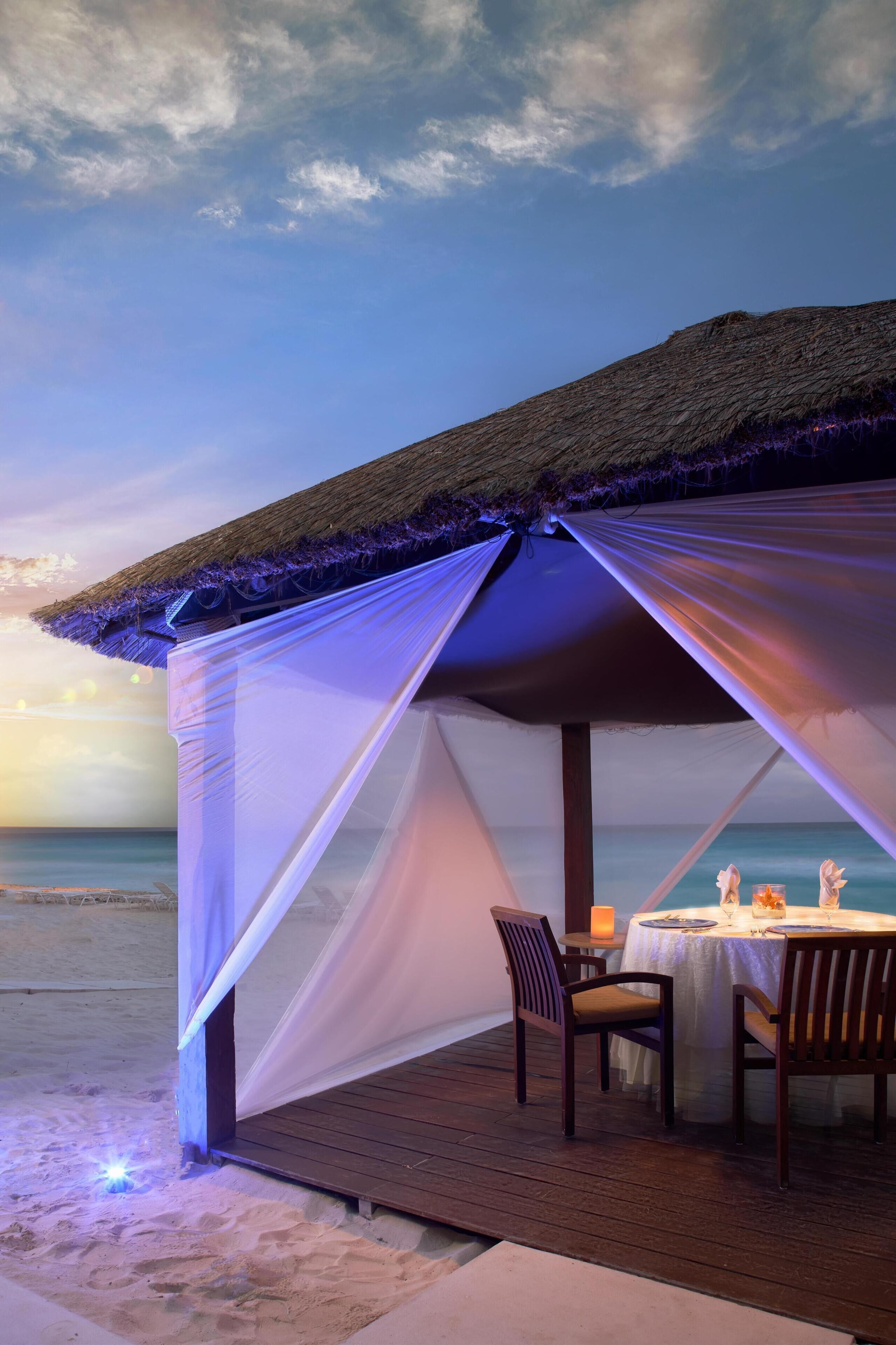Una carpa en la playa con una mesa y sillas, con vista al océano.