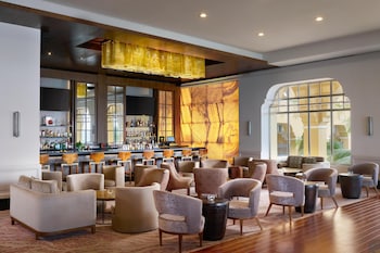 A hotel room with a large bed, a TV, a desk, and a view of the ocean. at Kempinski Hotel Cancun