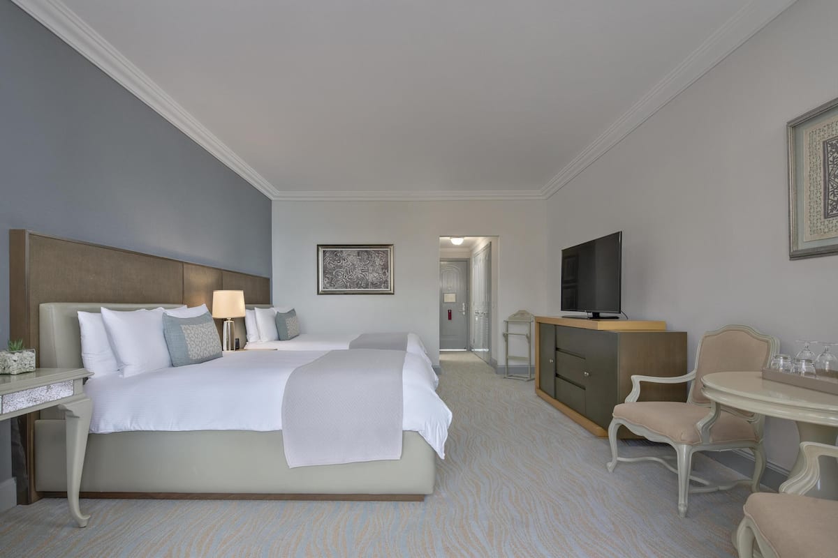 Une chambre d’hôtel avec un grand lit, des tables de chevet, une télévision, une table à manger et une chaise.