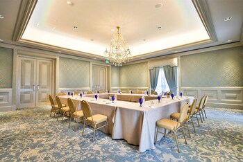 A formal dining room with a long table set for a meal, flanked by ornate chairs, a chandelier, and wall sconces. at Kempinski Hotel Cancun