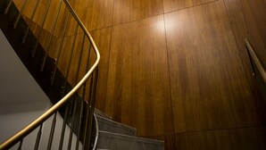 Un escalier moderne avec un revêtement mural en bois et une rampe en métal.