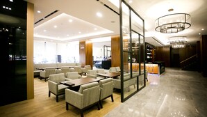 Un amplio vestíbulo de hotel con zona de estar, una recepción y una escalera.