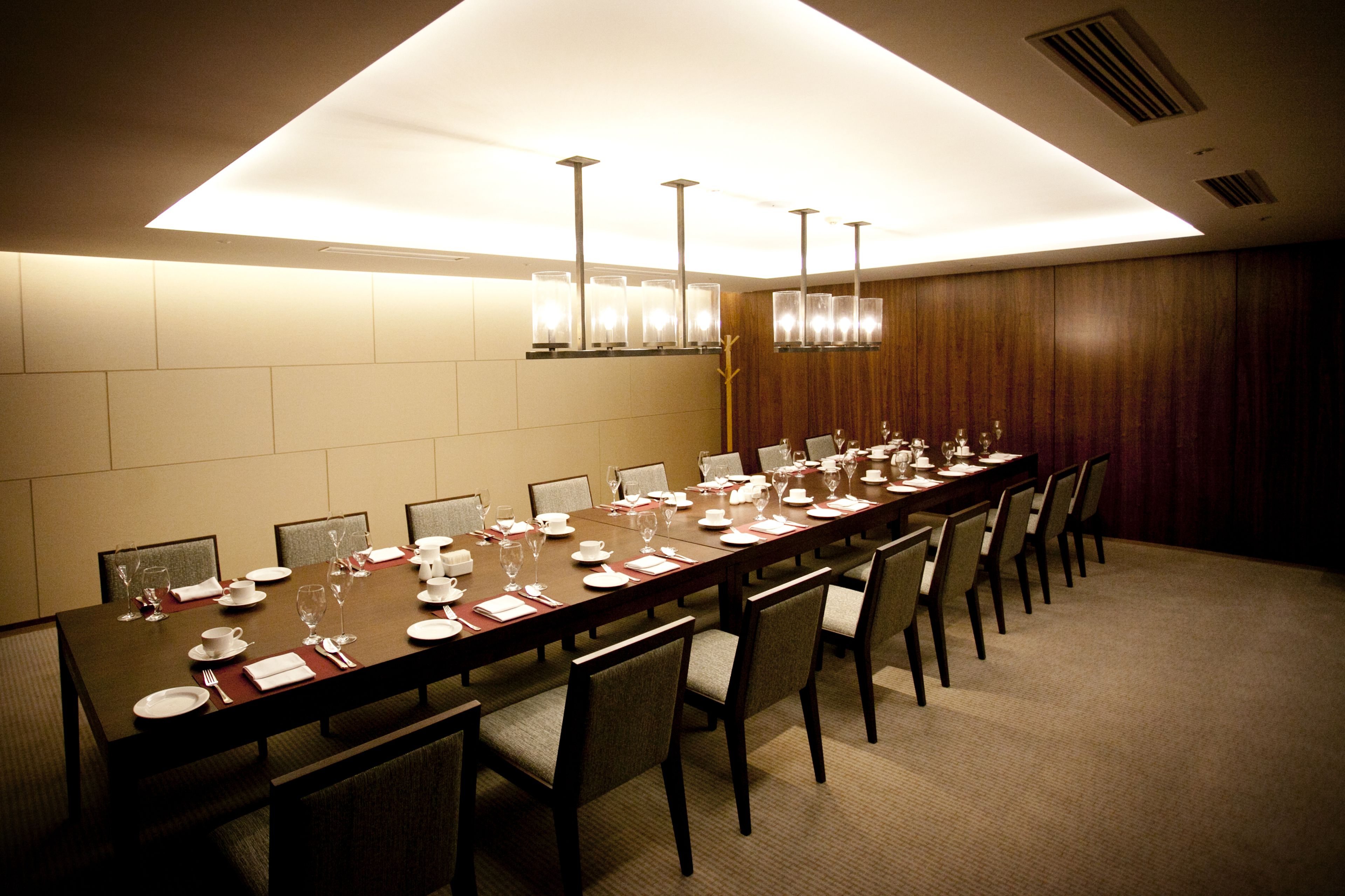 A conference room with a long table set for a meeting, equipped with chairs and a modern chandelier.