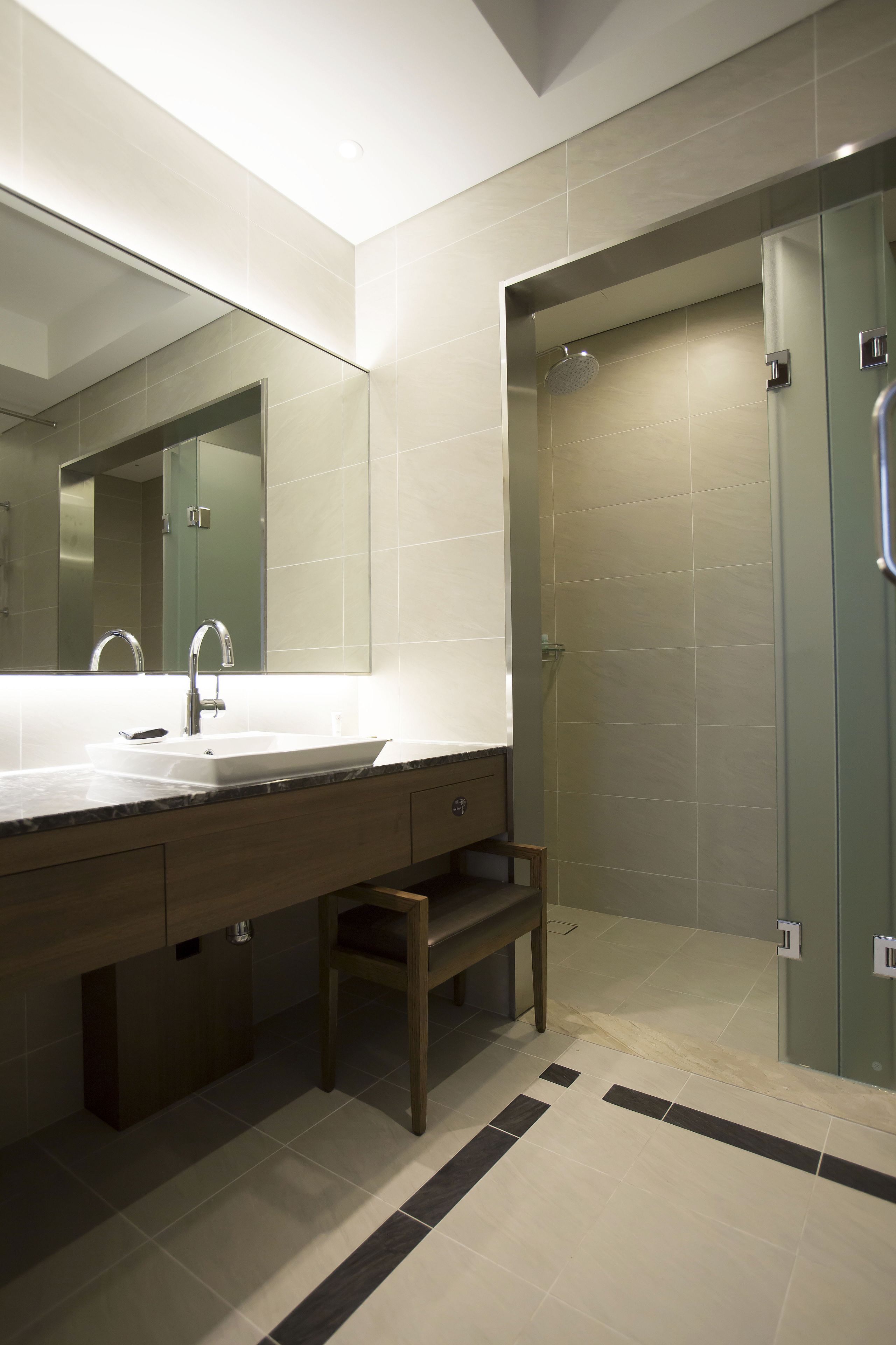 A modern bathroom with a large sink, mirror, and shower area.