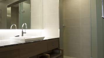 A modern bathroom with a large sink, mirror, and shower area.