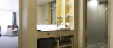A modern hotel bathroom with a large mirror, a sink, and a shower area.