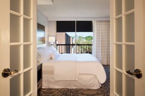 A hotel room with a large bed, a window with a view of buildings, and a balcony with a railing. - The Westin Princeton at Forrestal Village (Princeton)