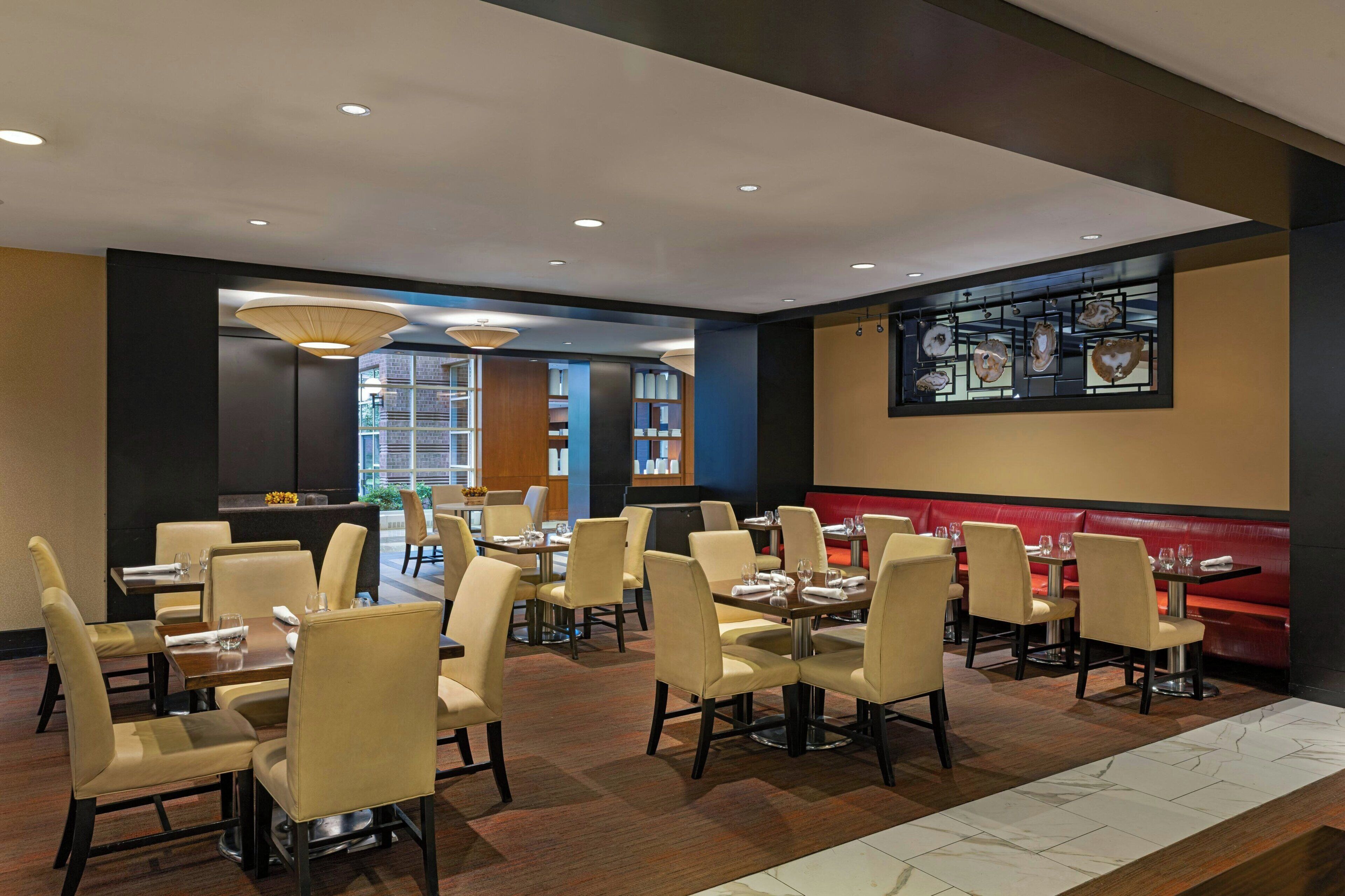 Un ristorante con diversi tavoli e sedie, un'area bar e un'ampia finestra vista.