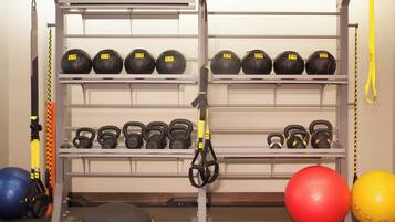 Une salle de sport équipée de matériel d’entraînement, notamment des kettlebells, des balles lestées et des systèmes d’entraînement en suspension TRX.