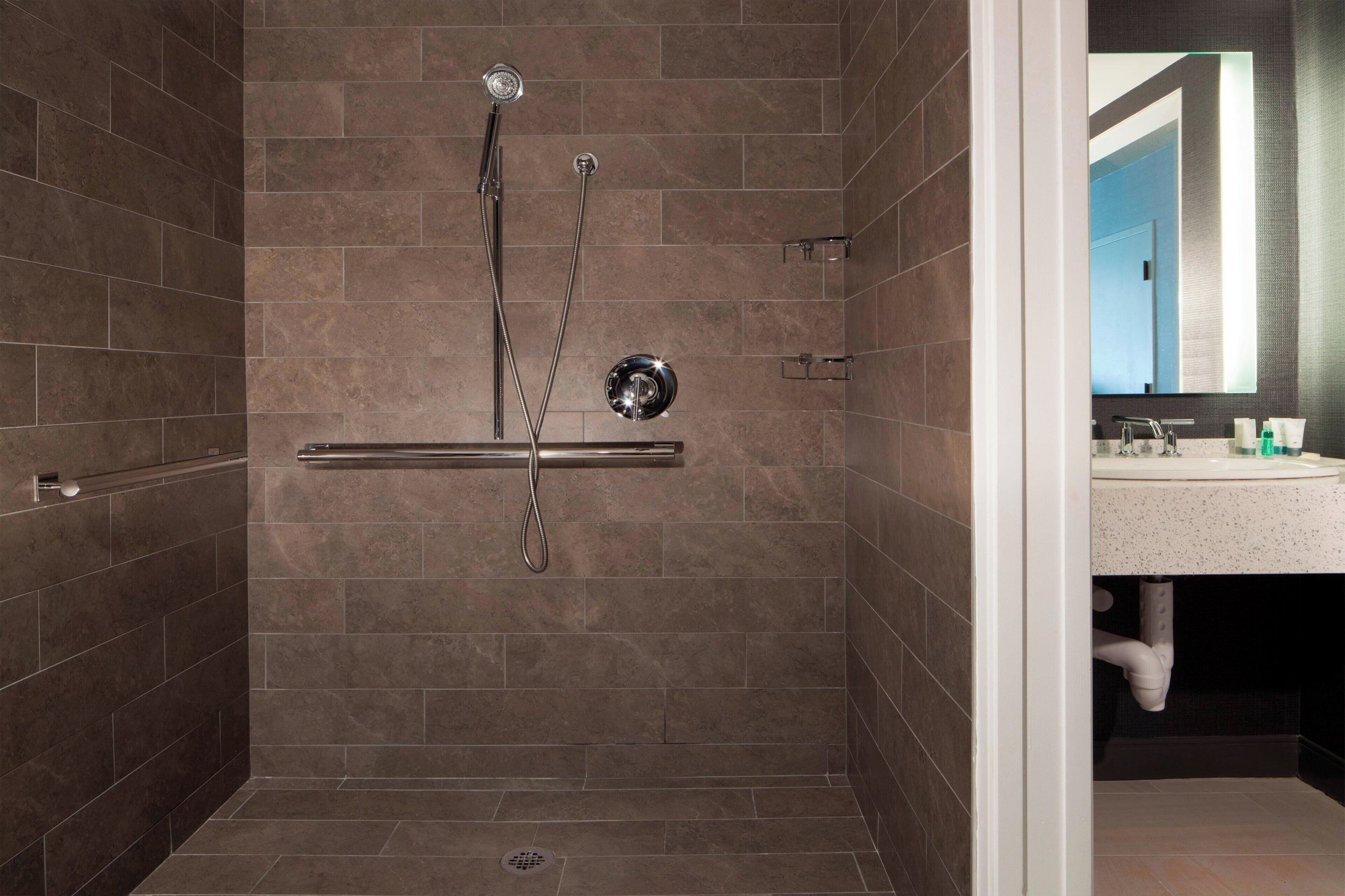 A modern bathroom with a walk-in shower, a glass-enclosed vanity, and a large mirror.