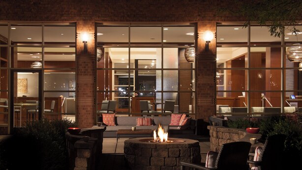 An outdoor seating area with a fire pit, stone walls, and modern furniture. - The Westin Princeton at Forrestal Village (Princeton)