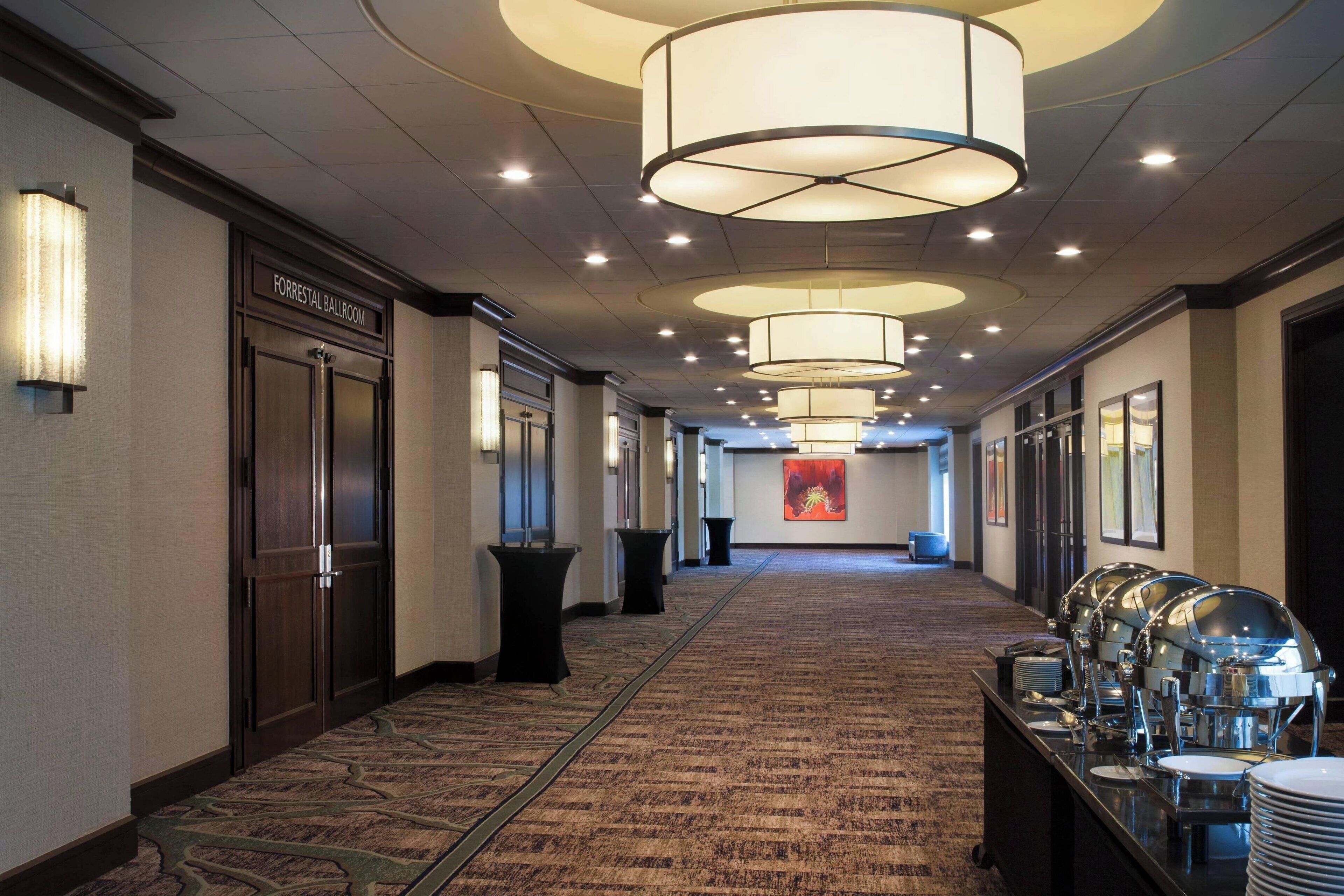 A hotel corridor with a buffet setup, a Forrester Ballroom sign, and a carpeted floor.