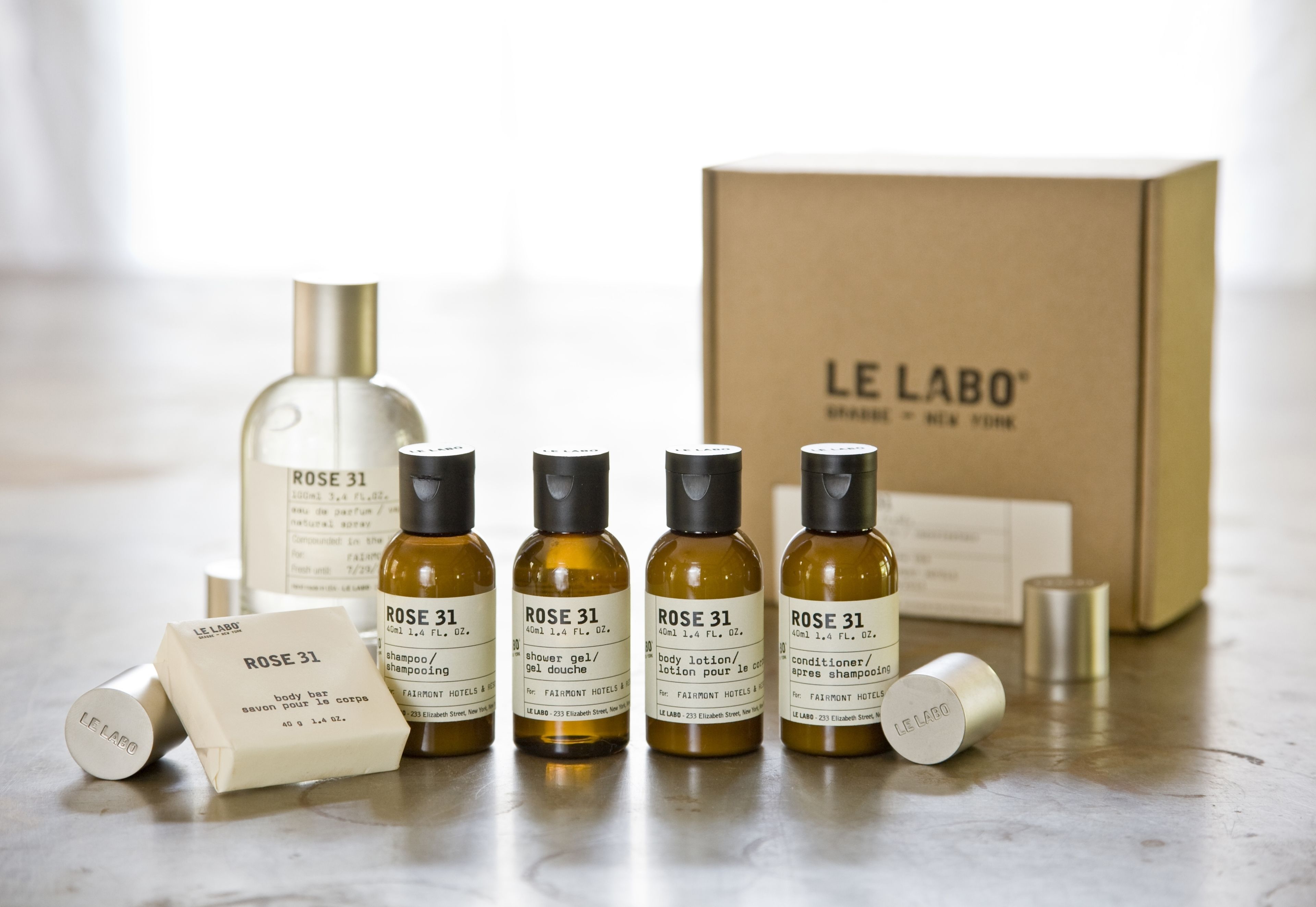 Ett set med produkter från Le Labo, Rose 31, inklusive schampo, balsam, kroppslotion och duschgel, placerat på ett bord med en kartonglåda i bakgrunden.