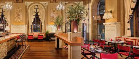 A spacious dining area with high ceilings, ornate ceiling details, and a central bar area.